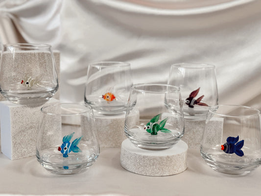 Green fish figurine inside a clear handmade stemless wine glass