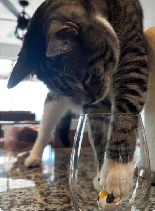 Hand-formed cat figurine displayed inside a clear stemless wine glass