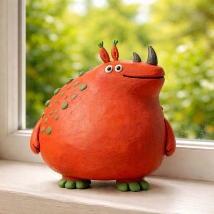 Orange handmade clay monster figurine with green spots and dark horns