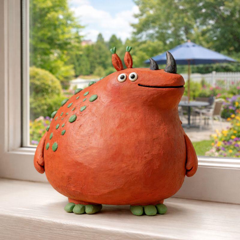 Orange handmade clay monster figurine with green spots and dark horns