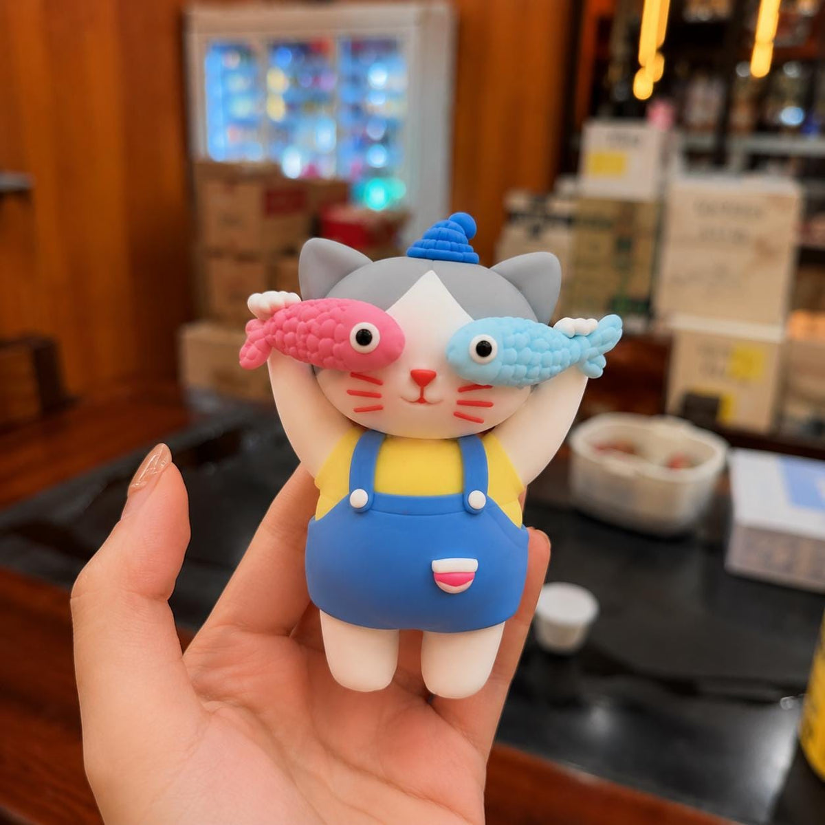 Handmade cat clay figurine holding pink and blue fish, image 1